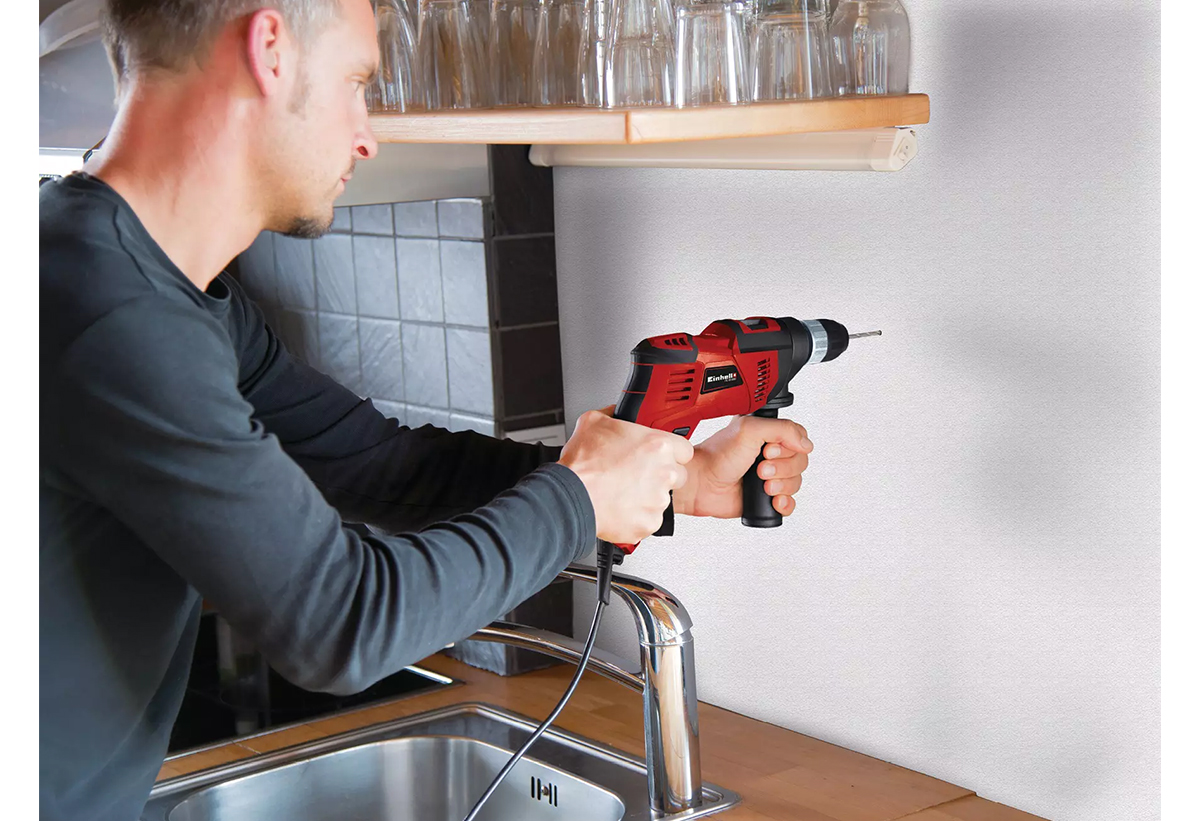 Απεικονίζεται άνδρας να χρησιμοποιεί το δράπανο σε τοίχο.